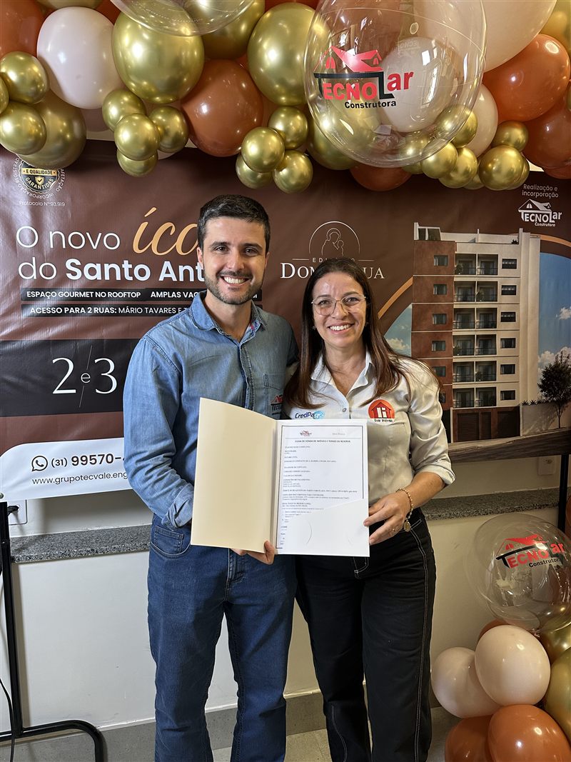 Casal que comprou o Dom Pádua segurando o contrato assinado, ao lado da equipe Tecnolar